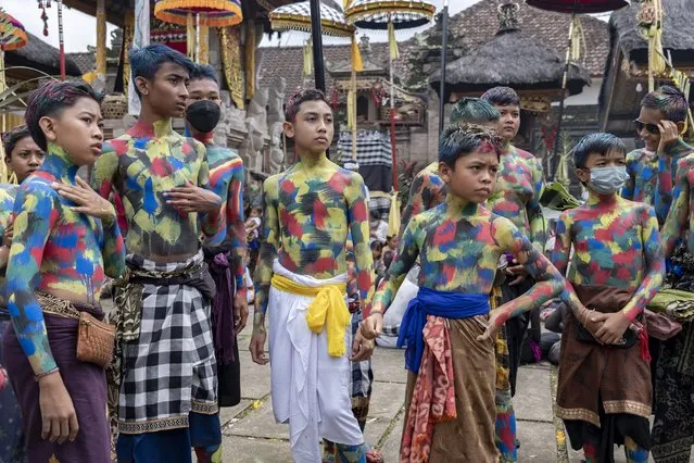 People wear body paint during the sacred Ngerebeg ritual at a village in Gianyar, Bali, Indonesia, 15 December 2021. The sacred Ngerebeg ritual takes place every six months and it is mainly aimed at driving all evil spirits out of the villages. During the ritual, participants decorate their body with colourful paint and march across the village. (Photo by Made Nagi/EPA/EFE)