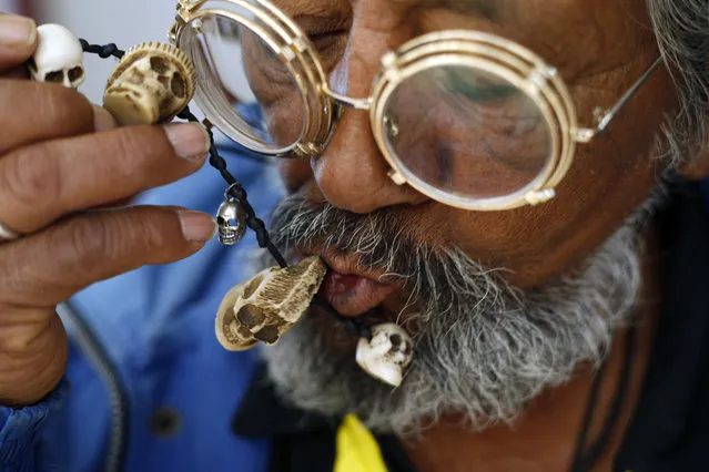 In this February 26, 2017 photo, a devotee of Saint Death or “La Santa Muerte” kisses a necklace adorned with miniature skulls during a religious service at Mercy Church on the edge of Mexico City's Tepito neighborhood. Santa Muerte devotees say she has millions followers and various names: the Death Saint, the White Girl, the Skinny One, or just Sister. (Photo by Marco Ugarte/AP Photo)
