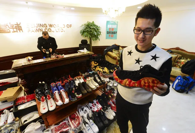 A man holds two sneakers of his collection of Nike Air Jordan as he sells them at a pawn shop in Beijing February 8, 2015. The man pawned a total of 283 pairs of his Nike Air Jordan sneakers collection for a million yuan ($160,000 USD), which he needed for the down payment of his wedding apartment. He had been collecting sneakers for over 10 years and he was planning to redeem them within the two months contract with the pawn shop, local media reported. (Photo by Reuters/Stringer)