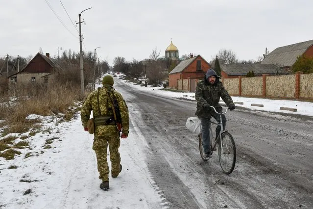 A Ukrainian serviceman patrols a street near the frontline with Russia-backed separatists in Verkhnotoretske village in Yasynuvata district, Donetsk region, eastern Ukraine, January 22, 2022. Ukrainians in the country's east are likely to be on the front lines of war if it comes, but they are far from the people making decisions about their fate. (Photo by Andriy Andriyenko/AP Photo)