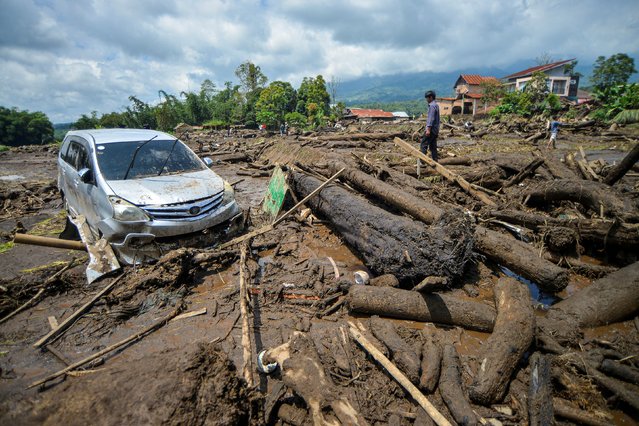 A man stands near a damaged car in an area affected by heavy rain brought flash floods and landslides in Agam, West Sumatra province, Indonesia, on May 12, 2024, in this photo taken by Antara Foto. (Photo by ggo El Fitra/Antara Foto via Reuters)