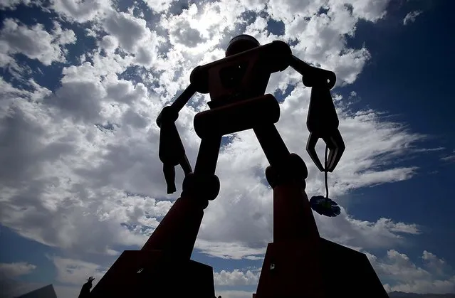 A man is dwarfed by a giant robot art sculpture on the Empire Polo Grounds at the Coachella Valley Music & Arts Festival at the Empire Polo Club in Indio, California, April 12, 2014. (Photo by Luis Sinco/Los Angeles Times/MCT)