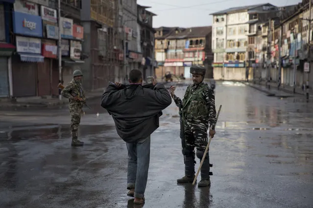 An Indian Paramilitary soldier orders a Kashmiri to lift his robe before frisking him  during curfew in Srinagar, Indian controlled Kashmir, Thursday, August 8, 2019. The lives of millions in India's only Muslim-majority region have been upended since the latest, and most serious, crackdown followed a decision by New Delhi to revoke the special status of Jammu and Kashmir and downgrade the Himalayan region from statehood to a territory. Kashmir is claimed in full by both India and Pakistan, and rebels have been fighting Indian rule in the portion it administers for decades. (Photo by Dar Yasin/AP Photo)