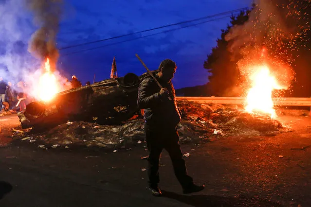 A fisherman walks past a barricade blocking a road during a protest calling on the government to help ease the economic effects of a harmful algal bloom that had affected their livelihoods at Ancud on Chiloe island in Chile, May 5, 2016. (Photo by Pablo Sanhueza/Reuters)