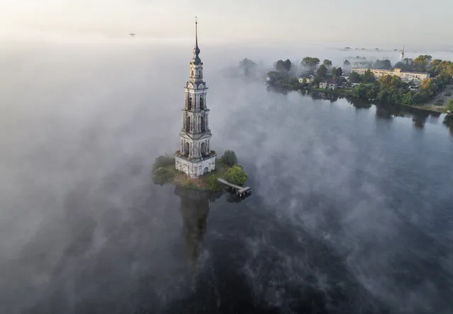 The famous Kalyazin Bell Tower, part of the submerged monastery of St. Nicholas, is seen in the morning fog in the town of Kalyazin located on the Volga River, 180 km (111 miles) north-east of Moscow, Russia, Monday, August 12, 2019. After the construction of the Uglich Dam in 1939 to form the Uglich Reservoir, the old parts of Kalyazin, including several medieval structures, were submerged under the reservoir's waters. (Photo by Dmitri Lovetsky/AP Photo)