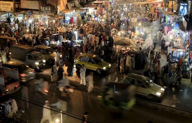Vehicles drive past as people shop at a market ahead of the Muslim festival of Eid al-Fitr, which marks the end of Ramadan, in Rawalpindi, Pakistan, July 13, 2015. (Photo by Faisal Mahmood/Reuters)