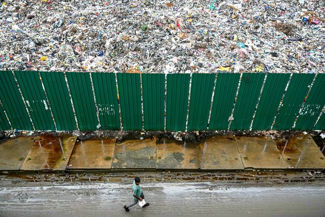 A man walks past a disposal site in Chennai, India, on Monday, July 15, 2024. (Photo by R.Satish Babu/AFP Photo)