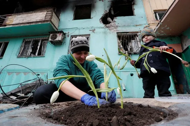 Local resident Viktoria Mukhina, 33, plants tulips with her daughter Miroslava near an apartment building damaged during Ukraine-Russia conflict in the southern port city of Mariupol, Ukraine on April 4, 2022. (Photo by Alexander Ermochenko/Reuters)