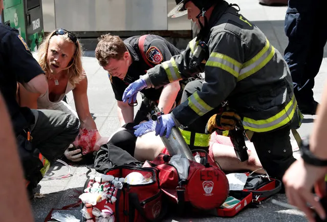 An injured woman is helped by emergency workers as she lies on the sidewalk in Times Square after a speeding vehicle struck pedestrians on the sidewalk in New York City, U.S., May 18, 2017. (Photo by Mike Segar/Reuters)