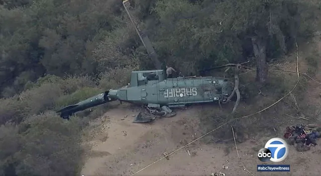 This ABC7 Los Angeles aerial video image shows emergency personnel next to a Los Angeles Sheriff Department helicopter after it crashed near San Gabriel dam in Azusa, Calif., on Saturday, March 19, 2022. Authorities are investigating the crash of a Los Angeles County Sheriff's Department rescue helicopter that left six people injured in mountains northeast of downtown LA. The department's Air Rescue 5 helicopter crashed shortly before 5 p.m. Saturday while responding to a vehicle that rolled over on a winding road in Angeles National Forest. (Photo by ABC7 Los Angeles via AP Photo)