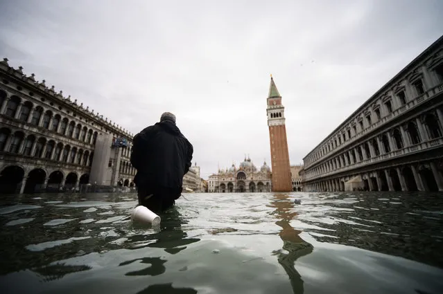 A man walks across the flooded St. Mark's Square, with St. Mark's Basilica (Rear L) and the Bell Tower on November 15, 2019 in Venice, two days after the city suffered its highest tide in 50 years. Flood-hit Venice was bracing for another exceptional high tide on November 15, as Italy declared a state of emergency for the UNESCO city where perilous deluges have caused millions of euros worth of damage. (Photo by Filippo Monteforte/AFP Photo)