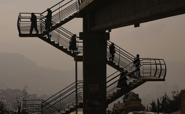 Smoke from fires fills the air in La Paz, Bolivia where pedestrians use stairs that allow them to cross over a road, Thursday, September 5, 2024. (Photo by Juan Karita/AP Photo)