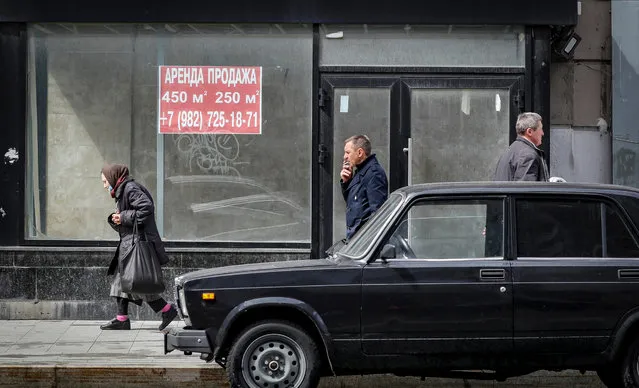 Russian people walk past the window of empty commercial premises in Moscow, Russia on May 19, 2022. As the result of sanctions imposed by the West on Russia, a number of international brands have announced the suspension or limitation of their business in Russia. (Photo by Yuri Kochetkov/EPA/EFE)