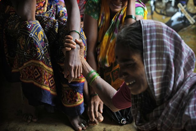 A woman holds a hand of her relative as family members of people who were trapped under rubble wail after a landslide washed away houses in Raigad district, western Maharashtra state, India, Thursday, July 20, 2023. While some people are reported dead many others feared trapped under piles of debris. (Photo by Rafiq Maqbool/AP Photo)