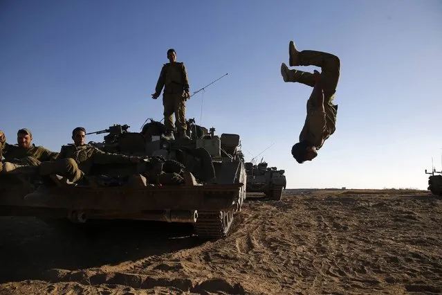 An Israeli soldier somersaults from an armoured personnel carrier (APC) stationed on a field outside the central Gaza Strip July 11, 2014. Prime Minister Benjamin Netanyahu said on Friday Israel has attacked more than 1,000 targets during a four-day-old offensive against Gaza militants and that “there are still more to go”. (Photo by Baz Ratner/Reuters)