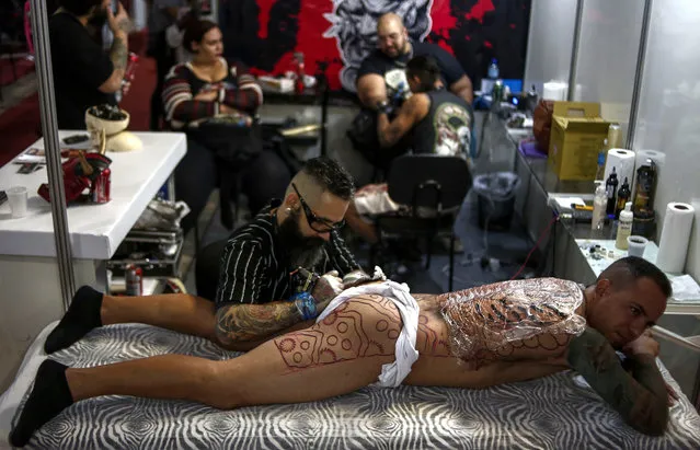 A tattoo artist makes a tattoo on a man during the Tattoo Week in Sao Paulo, Brazil, July 14, 2017. (Photo by Miguel Schincariol/AFP Photo)