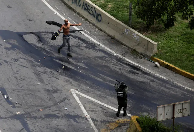 A demonstrator faces off with a member of the riot security forces during a strike called to protest against Venezuelan President Nicolas Maduro's government in Caracas, Venezuela, July 20, 2017. (Photo by Fabiola Ferrero/Reuters)