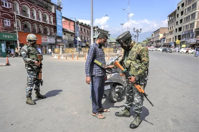 An Indian paramilitary soldier checks a civilian as they guard in Srinagar, Indian controlled Kashmir, Thursday, June 2, 2022. Assailants fatally shot a Hindu bank manager in Indian-controlled Kashmir on Thursday, said police, who blamed militants fighting against Indian rule for the attack. (Photo by Mukhtar Khan/AP Photo)