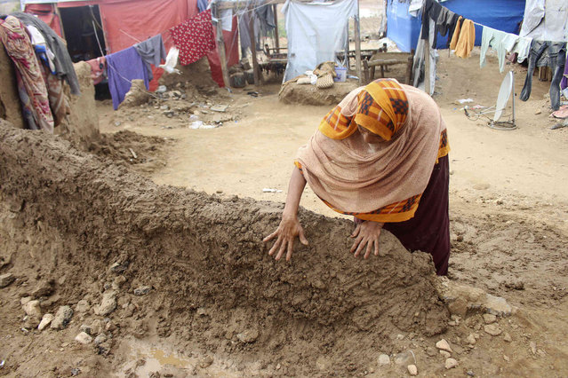 A woman builds a mud barrier to keep out floodwaters near the city of Abs in southwest Yemen after heavy seasonal rains in country have resulted in rising floodwaters on Thursday, August 8, 2024. (Photo by Eissa Ahmed/AP Photo)