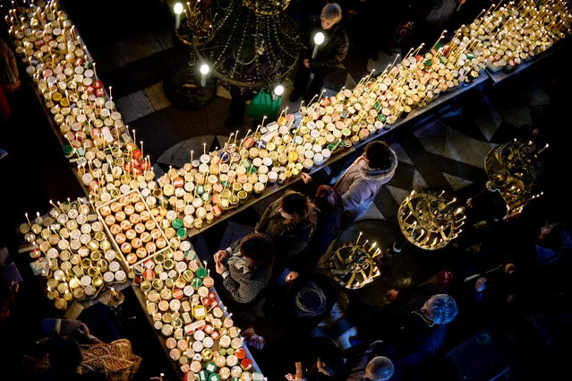 Bulgarian Orthodox faithful light candles attached to jars of honey during a holy mass for the “sanctification of honey” at the Presentation of the Blessed Virgin church in the town of Blagoevgrad, Bulgaria, 10 February 2020. Honey and beehives are sanctified by performing rituals for health and prosperity. On St. Haralambos' Day, who according to tradition is the lord of all illnesses, sick or blind people go to church and pray for healing. Housework is strictly forbidden on that day over fears of any illness, with women being only allowed to bake traditional bread for the occasion. The honey is then consecrated at the local church and then all the bread is coated with that honey. The rest of it will be kept as a remedy at home. (Photo by Borislav Troshev/EPA/EFE)