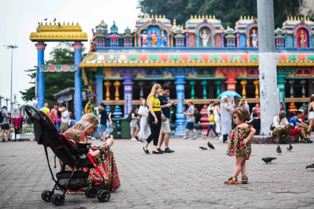 A tourist takes pictures of a child at a temple in Batu Caves, near Kuala Lumpur on August 6, 2019. (Photo by Mohd Rasfan/AFP Photo)