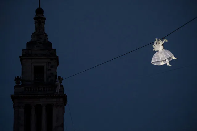 A performer is suspended from high-wires during the outdoor aerial performance of the show “Place des Anges” (Angels' square), performed by French theatre producers Gratte Ciel, in Kingston up Hull, north east England, on July 2, 2016. White-clad angels – les anges – appear high on rooftops around Hull College and Queens Gardens, before taking to the air for magical and occasionally mischievous antics above the crowds below. As the event reaches its climax, thousands of white feathers are released, falling from the sky in cascades, to create an extraordinary “snowstorm” for the audience to dance and play in. (Photo by Oli Scarff/AFP Photo)
