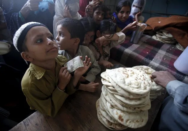 Children stand in line to get subsidized bread at a food distribution point in Karachi, Pakistan, August 20, 2015. (Photo by Athar Hussain/Reuters)