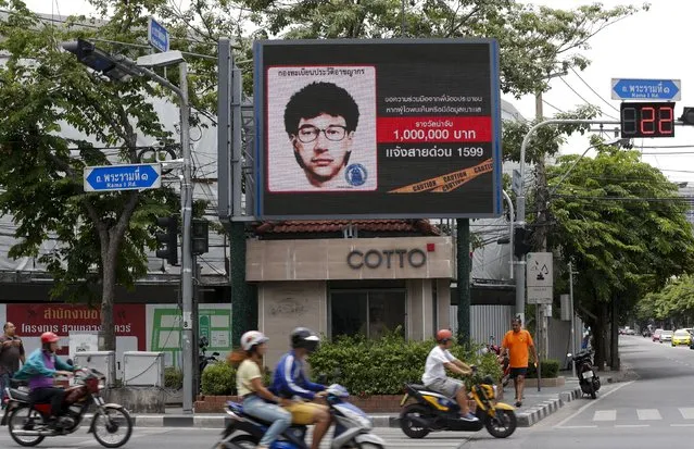 People ride their motorcycles past a digital billboard showing a sketch of the main suspect in Monday's attack on Erawan shrine, in Bangkok, Thailand, August 23, 2015. Thai authorities have tripled to $85,000 a reward for information leading to the arrest of the main suspect in the country's worst ever bombing. (Photo by Chaiwat Subprasom/Reuters)