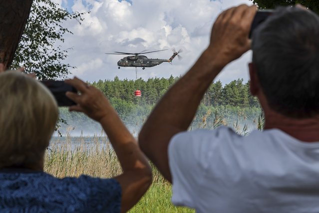 A Bell CH-53 German Bundeswehr army firefighter helicopter loads water from a sea  in Falkenberg, Germany, Tuesday, July 26, 2022. Firefighters in Brandenburg continue to fight a large forest fire in the Elbe-Elster district. Since yesterday, it has been burning on an area of 800 hectares. First residents had to leave their homes. (Photo by Jan Woitas/dpa via AP Photo)