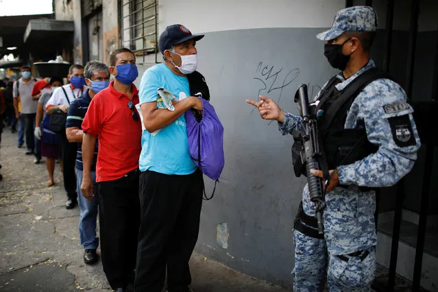 A policeman asks for documents in a checkpoint during a police and army joint operation as part of security measures to keep people out of city downtown markets during a quarantine throughout the country to curb the spread of the coronavirus disease (COVID-19), in San Salvador, El Salvador on April 20, 2020. (Photo by Jose Cabezas/Reuters)