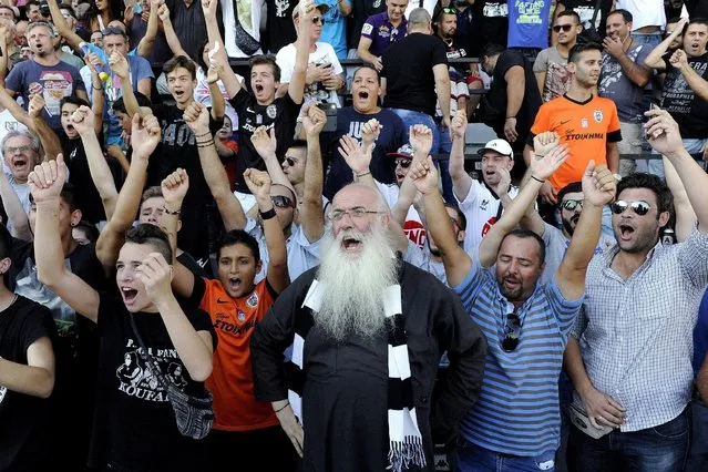 PAOK fans, among them a Greek Orthodox priest (C), cheer for Bulgarian forward Dimitar Berbatov (not pictured) during his presentation at the Toumba Stadium in Thessaloniki, Greece, September 3, 2015. Berbatov was treated to a hero's welcome on Thursday as 10,000 jubilant PAOK Salonika fans turned up to greet the club's new signing at their Toumba Stadium. (Photo by Alexandros Avramidis/Reuters)