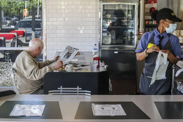 Waffle House's Tiffany, right, get To Go orders ready as a seated guest enjoys his meal on Monday, April 27, 2020, at The Waffle House in Brookhaven, Ga. Restaurants around metro Atlanta began to reopen dining rooms as restrictions related to the coronavirus pandemic are lifted. (Photo by John Spink/Atlanta Journal-Constitution via AP Photo)
