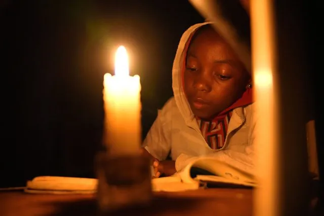 Tracy Carlos uses a candlelight to do her homework in Mabvuku on the outskirts of Harare on Wednesday, August 3, 2022.Because of lengthy power cuts, the children do their homework by a candle, although their parents press them to use it sparingly. Her father Jeff Carlos says he gets about $100 dollars a month from his job as an overnight security guard for a church and the bar next door. Rising prices and a fast-depreciating currency have pushed many Zimbabweans to the brink, reminding people of when the southern African country faced world-record inflation of 5 billion % in 2008. (Photo by Tsvangirayi Mukwazhi/AP Photo)