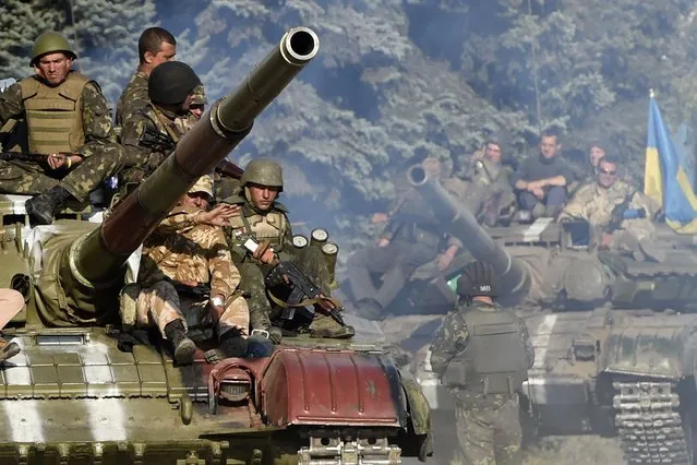 Ukrainian army soldiers ride a tank on a road near where pro-Russian separatists fired heavy artillery, on the outskirts of the key southeastern port city of Mariupol, on September 5, 2014. Ukraine and pro-Russian rebels agreed on September 5 on ceasefire aimed at halting nearly five months of war that plunged relations between Russia and the West into their worst crisis since the Cold War. (Photo by Philippe Desmazes/AFP Photo)