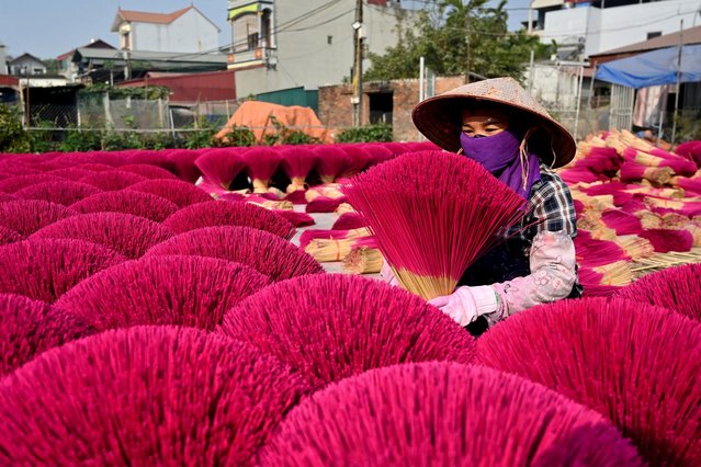 A worker arranges dried incense sticks to dry in a courtyard in Quang Phu Cau village on the outskirts of Hanoi on January 21, 2025, ahead of Lunar New Year celebrations, known in Vietnam as Tet. Families living and working in the “incense village” of Quang Phu Cau now also make sticks in yellow, blue and green, catering to visitors eager to snap shots for Instagram. (Photo by Nhac Nguyen/AFP Photo)