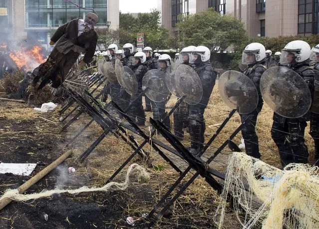Belgian riot police officers stand guard behind an effigy depicting European Agriculture and Rural Development Commissioner-designate Phil Hogan during clashes as farmers and dairy farmers from all over Europe take part in a demonstration outside an European Union farm ministers emergency meeting at the EU Council headquarters in Brussels, Belgium, September 7, 2015. (Photo by Yves Herman/Reuters)