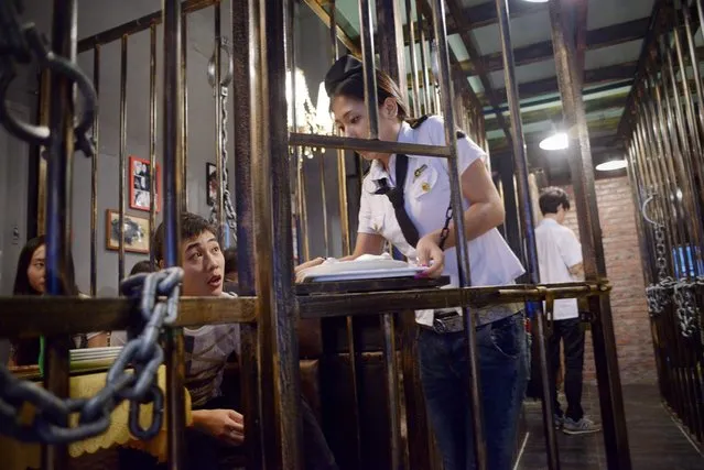 This picture taken on September 9, 2014 shows a waiteress handing over food to customers at a prison themed restaurant in Tianjin. As more themed restaurants are popular in China, a “prison style” restaurent in Tianjin is aimed at reminding people to observe the law and to be good citizens. (Photo by Wang Zhao/AFP Photo)