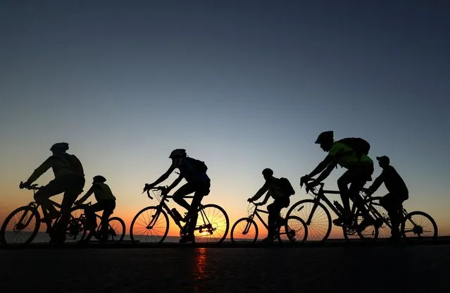 Palestinians ride bicycles at sunset along the shoreline in Gaza City, on August 23, 2022. (Photo by Mohammed Abed/AFP Photo)