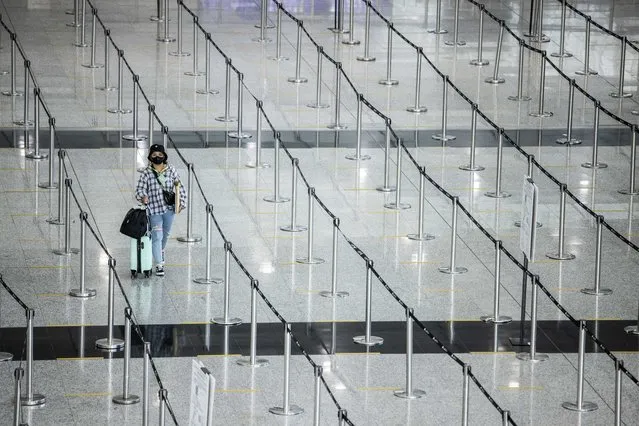 A woman arrives at Hong Kong International Airport before making her way to hotel quarantine on September 23, 2022. Hong Kong announced on September 23 it will end mandatory hotel quarantine, scrapping some of the world's toughest travel restrictions that have battered the economy and kept the finance hub internationally isolated. (Photo by Isaac Lawrence/AFP Photo)