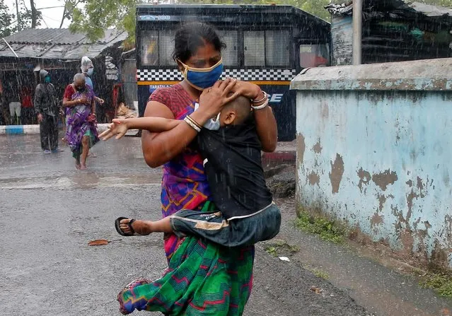 A woman carries her son as she tries to protect him from heavy rain while they rush to a safer place, following their evacuation from a slum area before Cyclone Amphan makes its landfall, in Kolkata, India, May 20, 2020. (Photo by Rupak De Chowdhuri/Reuters)