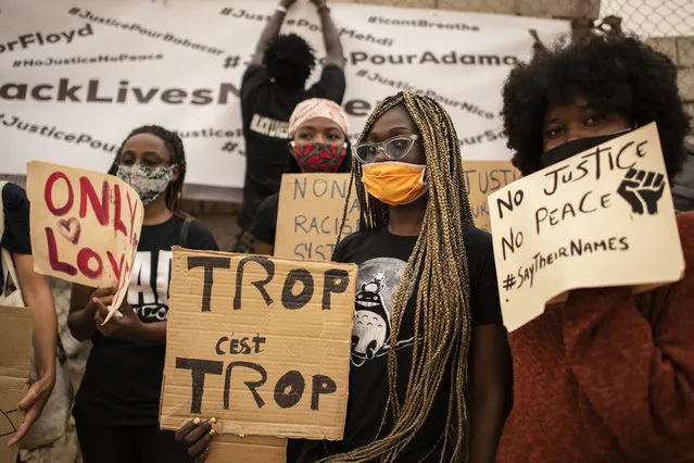 Protesters hold placards at a demonstration against the killing of George Floyd by police officers in Minneapolis, USA, held in front of the African Renaissance Monument in Dakar, Senegal Saturday, June 6, 2020. His death has led to Black Lives Matter protests in many countries and across the US. Placard in center in French reads “Too much is too much”. (Photo by Sylvain Cherkaoui/AP Photo)
