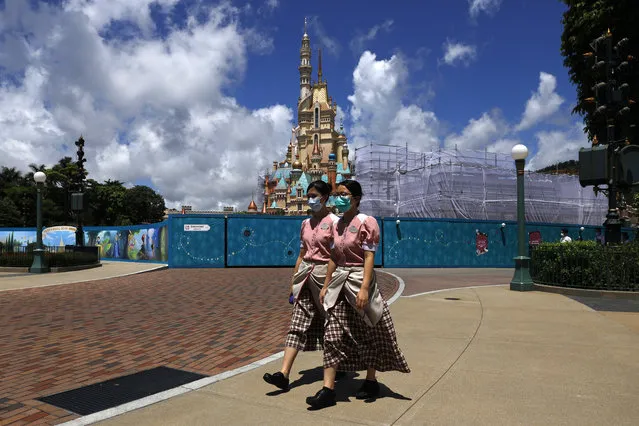 Employees wearing face masks to prevent the spread of the new coronavirus, walk through  the Hong Kong Disneyland on Wednesday, June 17, 2020, a day before the theme park reopen after nearly four months of closure due to the coronavirus pandemic. (Photo by Kin Cheung/AP Photo)