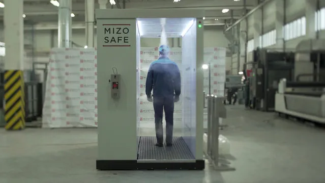 An employee walks through a disinfection tunnel manufactured by Russian company Mizotty at the company's factory in Penza, Russia on June 17, 2020, in this still image taken from undated handout video. (Photo by Mizotty/Reuters TV via Reuters)