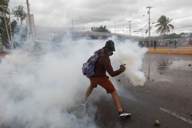 A supporter of Salvador Nasralla, presidential candidate for the Opposition Alliance Against the Dictatorship, throws a tear gas canister back to police during a protest while awaiting official presidential election results in Tegucigalpa, Honduras November 30, 2017. (Photo by Jorge Cabrera/Reuters)