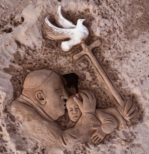A sand sculpture by artist Nicola Urru (C) with the effigy of Pope Frances embracing a child and holding a crosier in the shape of a cross with a dove at the top is on display on the beach of Sassari, Italy, 28 February 2025. Nicola Urru created the sand sculpture as a prayer motif for the pontiff who was admitted to Rome's Gemelli Hospital on 14 February, due to a respiratory tract infection. (Photo by Nicola Urru/EPA)