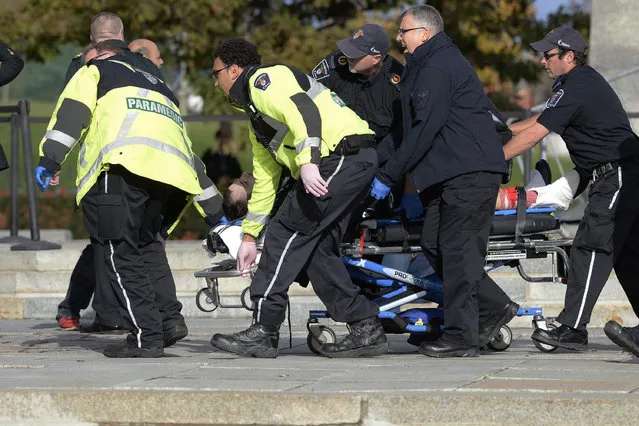 Paramedics and police pull a victim away from the Canadian War Memorial in Ottawa on Wednesday October 22, 2014. (Photo by Adrian Wyld/AP Photo/The Canadian Press)