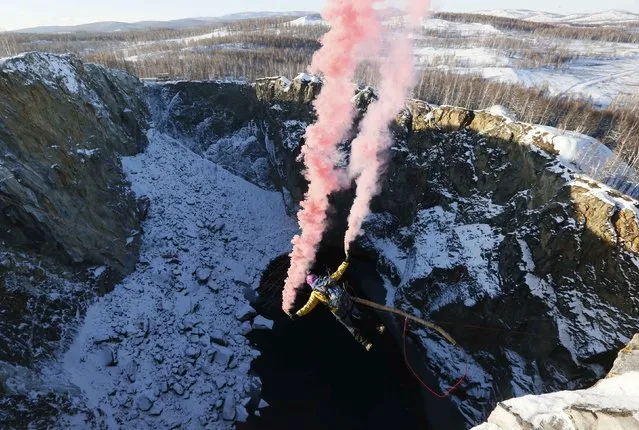 A member of the “Exit Point” amateur rope-jumping group takes a rope jump from a 120-metre (394 feet) high rock down to a man-made crater called “Tuimsky Proval” (Tuimsky cavity), with the air temperature at about minus 15 degrees Celsius (5 degrees Fahrenheit), outside the town of Tuim in Khakassia region, October 18, 2014. (Photo by Ilya Naymushin/Reuters)