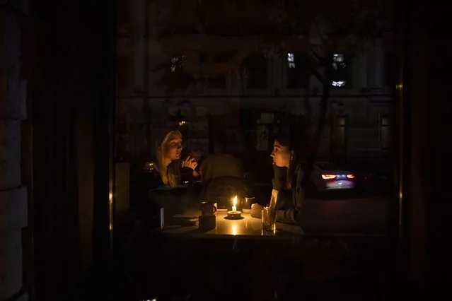 Women sit in candle light in a restaurant on a dark street on November 02, 2022 in Kyiv, Ukraine. Electricity and heating outages across Ukraine caused by missile and drone strikes to energy infrastructure have added urgency preparations for winter. (Photo by Ed Ram/Getty Images)