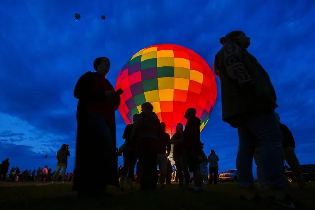 Attendees walk past a hot air balloon as it is lit by flame while being prepared for take off on the first day of the 2015 Albuquerque International Balloon Fiesta in Albuquerque, New Mexico, October 3, 2015. (Photo by Lucas Jackson/Reuters)