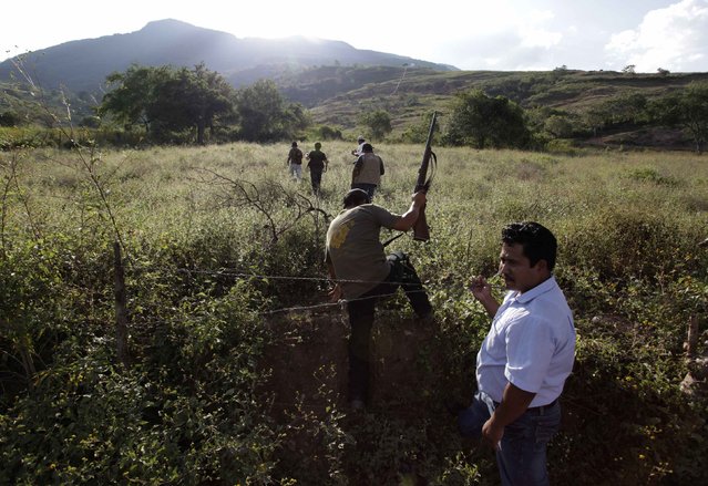Vigilantes walk into a field where a man, accused of having raped several children, allegedly took them in Acatempa October 28, 2014. Vigilantes detained the man after one child stepped forward and told his father that the man had threatened to skin him if he would not go with him, according to local media. The man, who denies the charges, was convicted in a quick trial let by the vigilantes and then handed over to the authorities. (Photo by Daniel Becerril/Reuters)